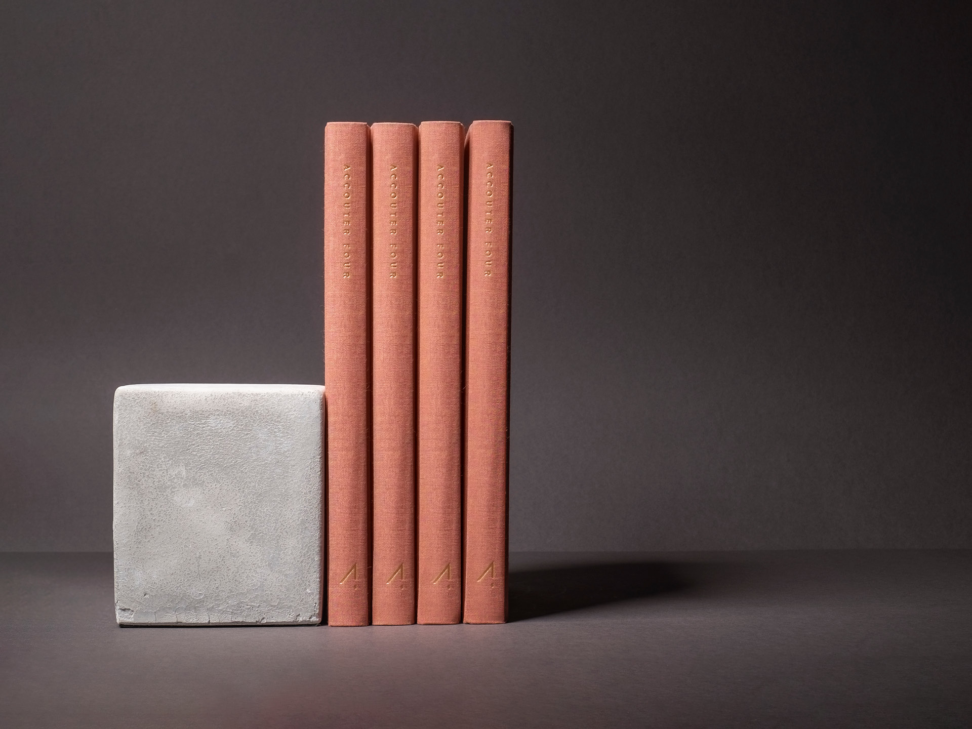 Four copper foiled books standing on end next to a concrete block