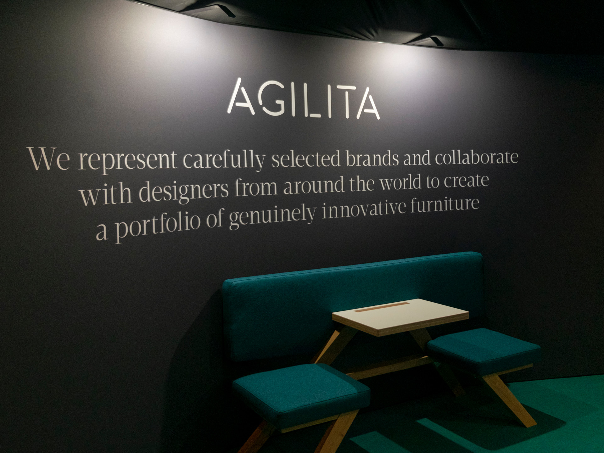 A photo fo the Agilita exhibition wall with logotype and large statement