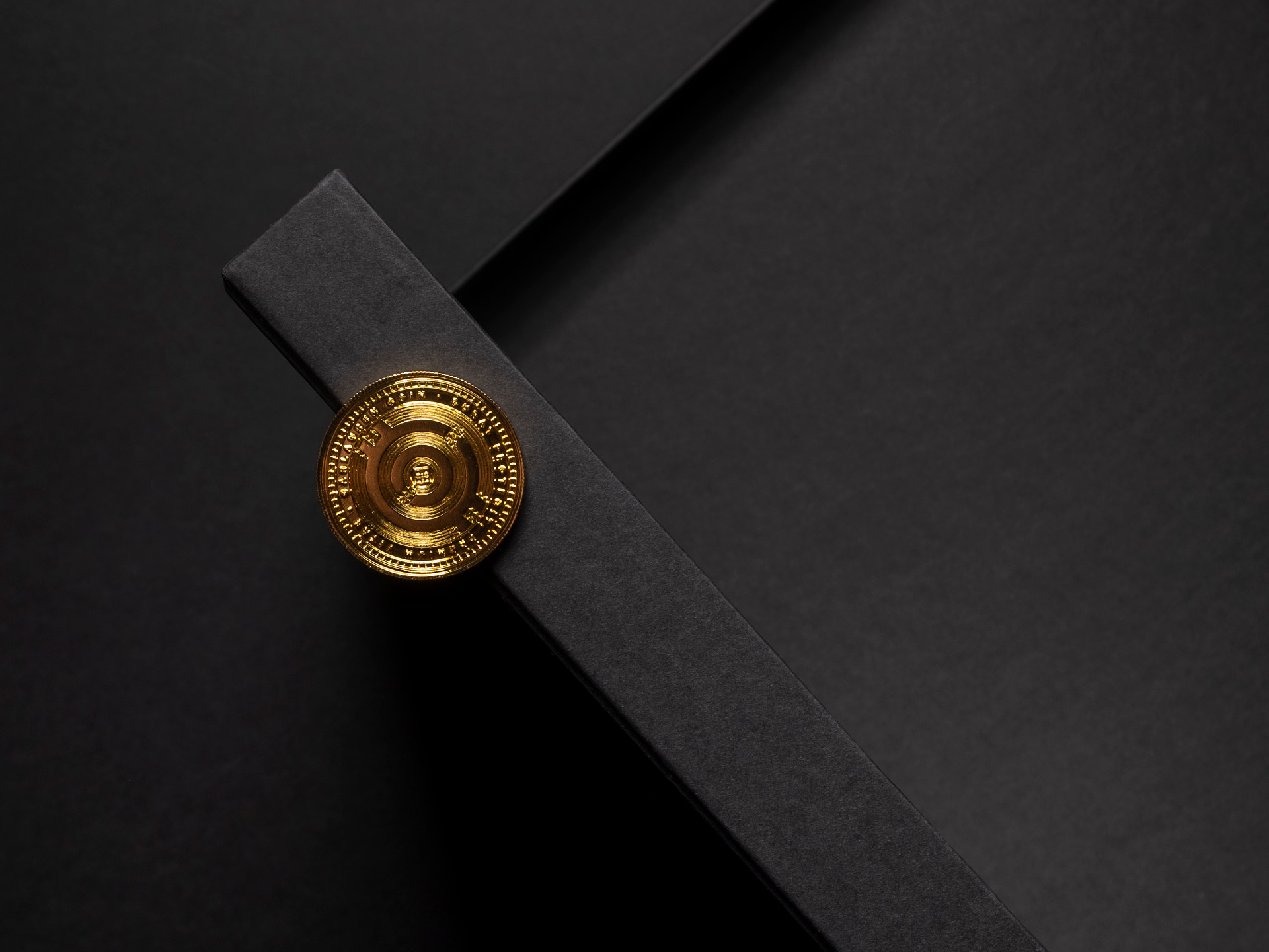 A golden coin positioned on the edge of a black box