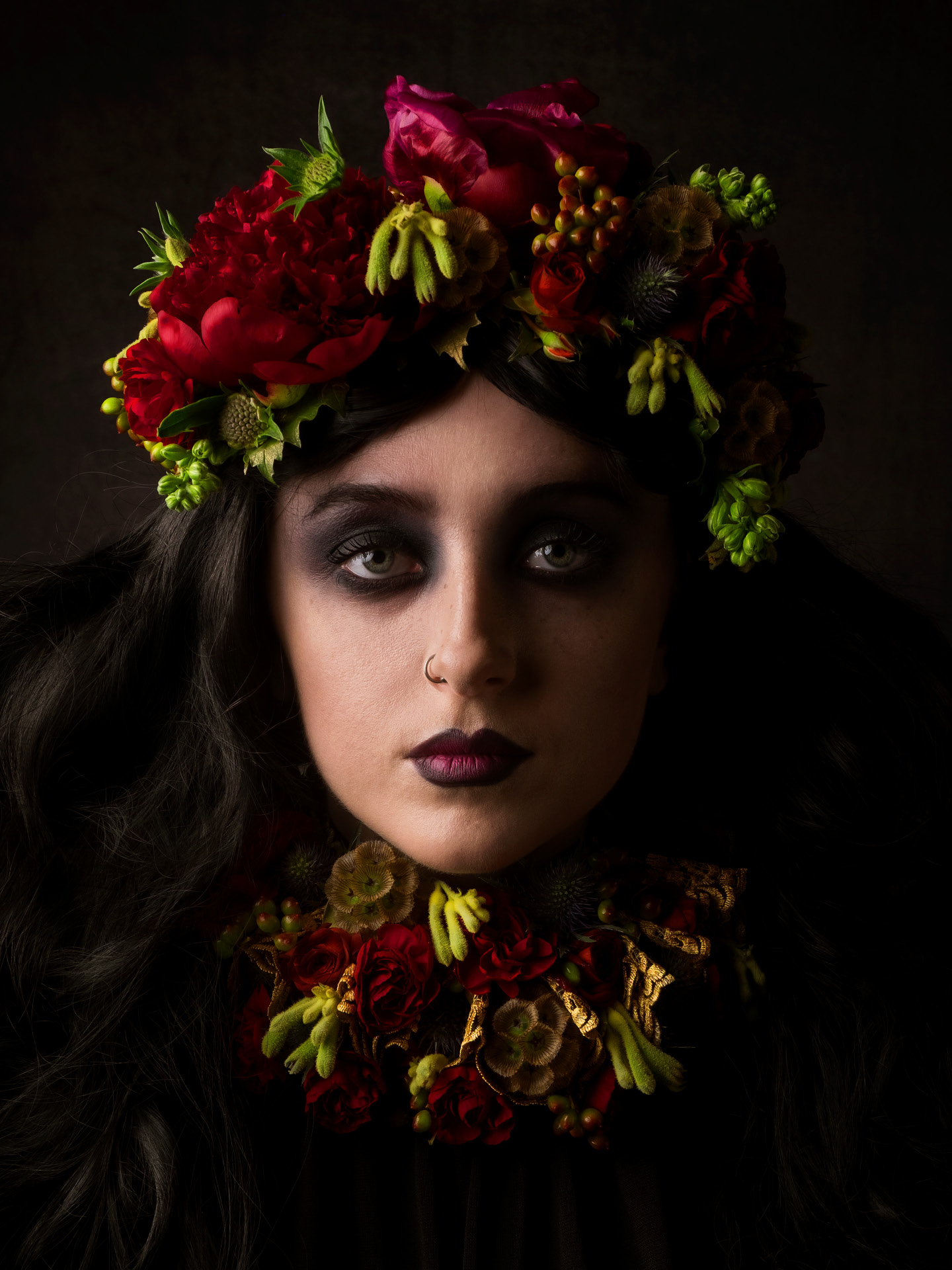 Portrait photography of model Bethan Perkins with coral crown and neck ruffle with dark makeup on her eyes and lips, with nose piercing by Ben Budden