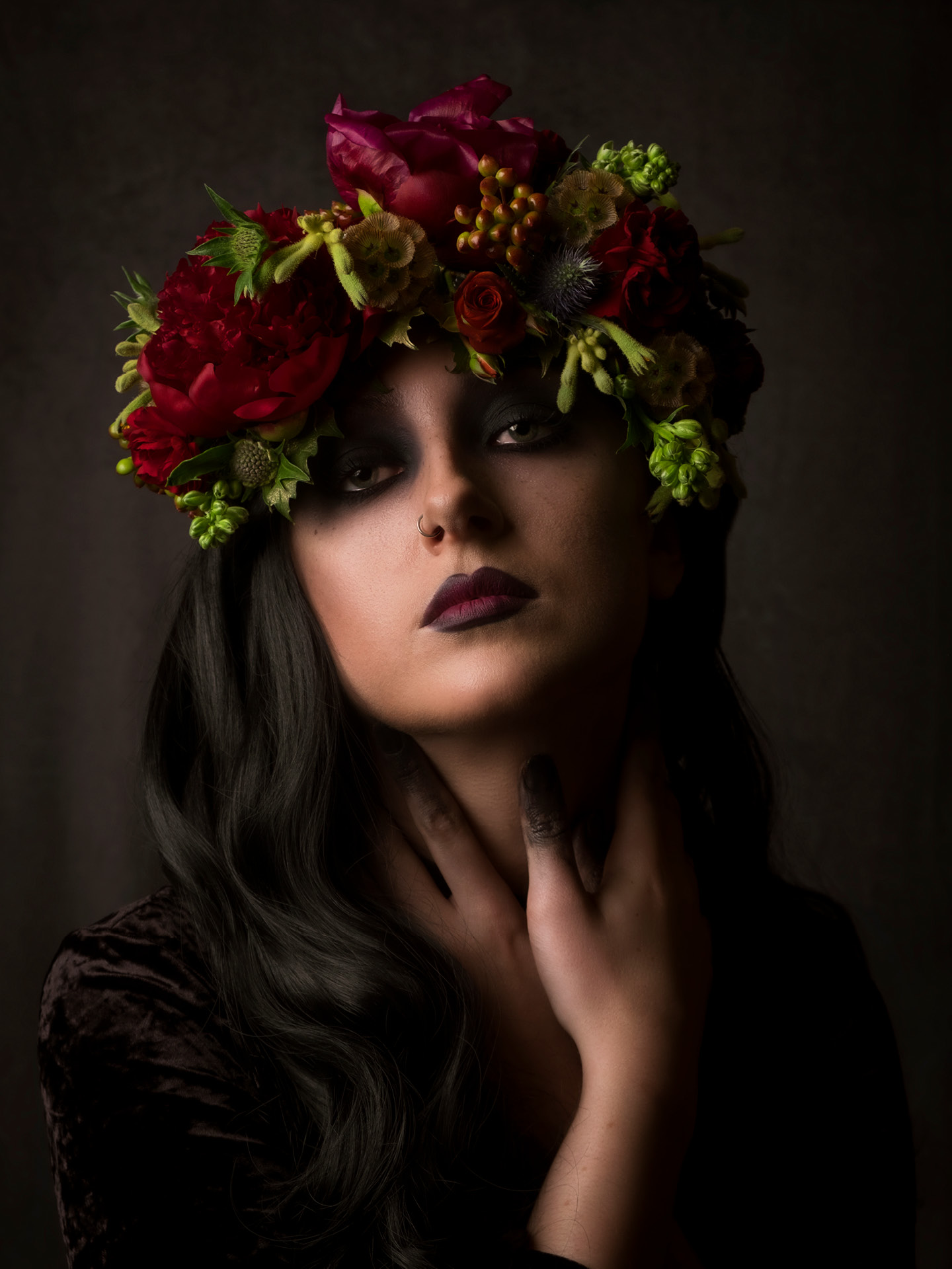 Portrait photography of model Bethan Perkins drawing particular attention to the floral head crown and deep black of the make-up on the finger tips