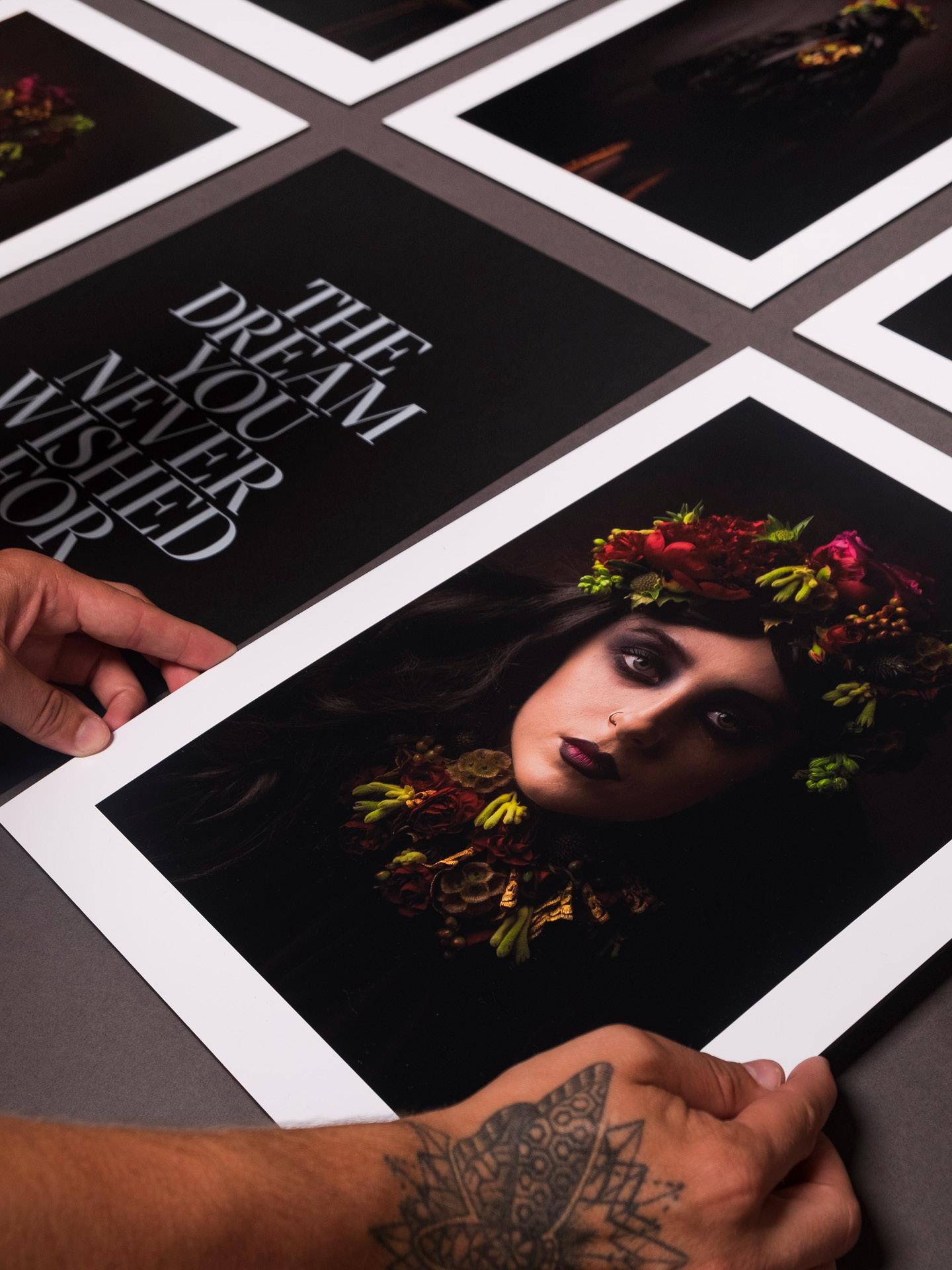 A couple of hands arranging the printed photographs and title sheets on a dark paper stock